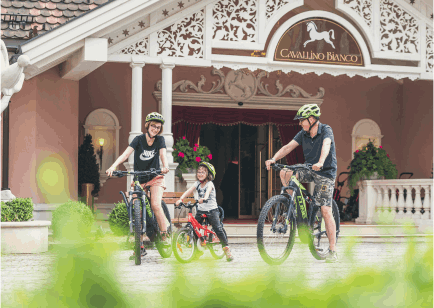 Mamma, papà e bambino in mountain bike fuori dall'hotel.