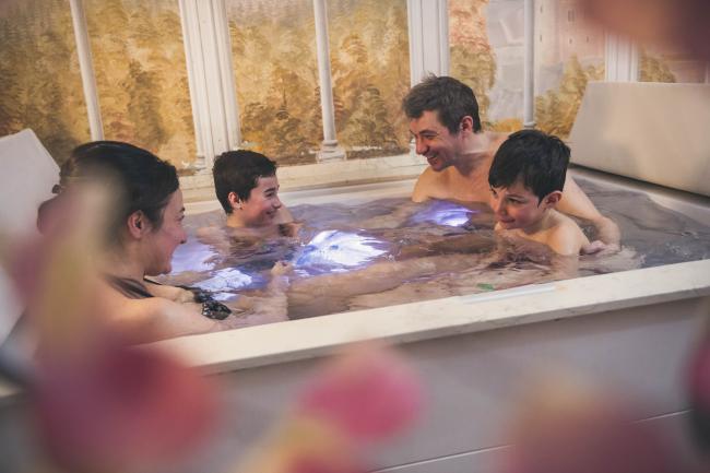 Famiglia con bimbi fa il bagno nella vasca dell'Hotel con spa per bambini.