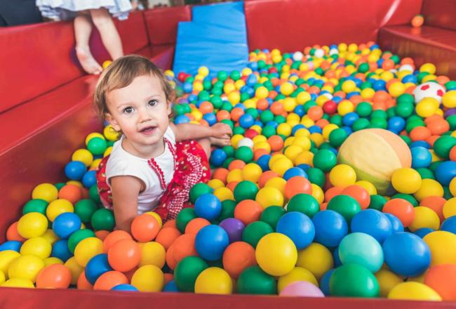 Bambina in vasca di palline nel miglior hotel per bambini