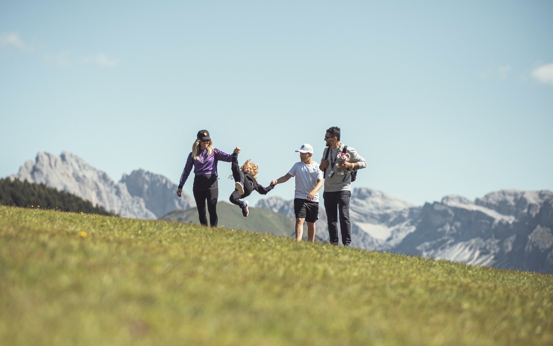 A family on a hike through the green meadows of the Dolomites.