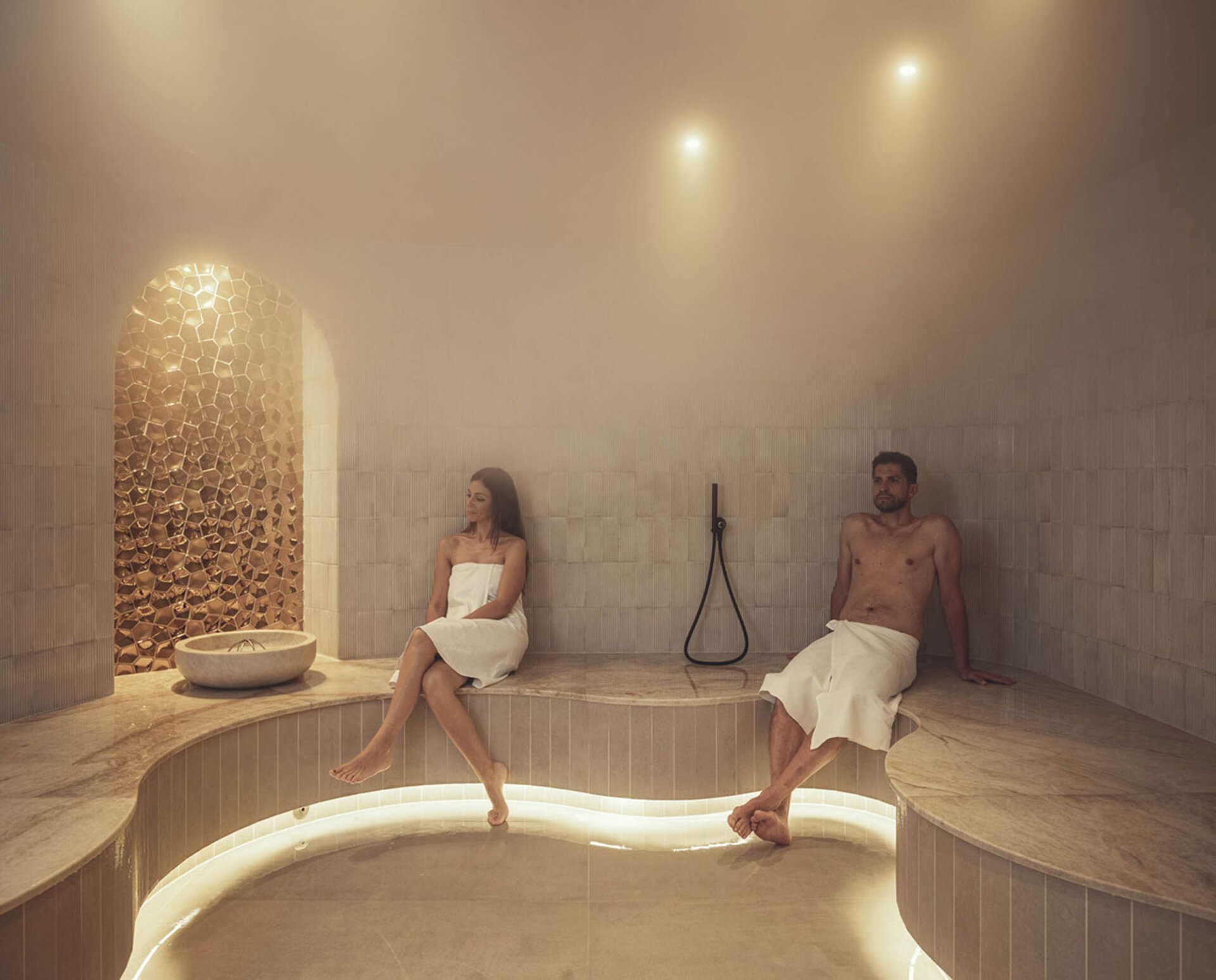 A man and woman in the Turkish bath of the hotel with spa for families in Italy.