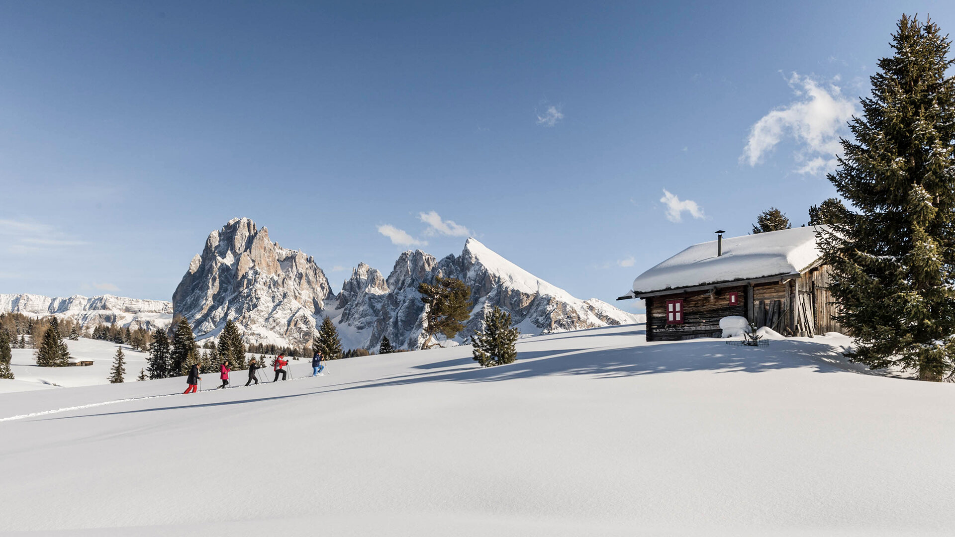 Famiglia in ciaspolata sulla neve cammina verso il rifugio - hotel per famiglie in Alto Adige.