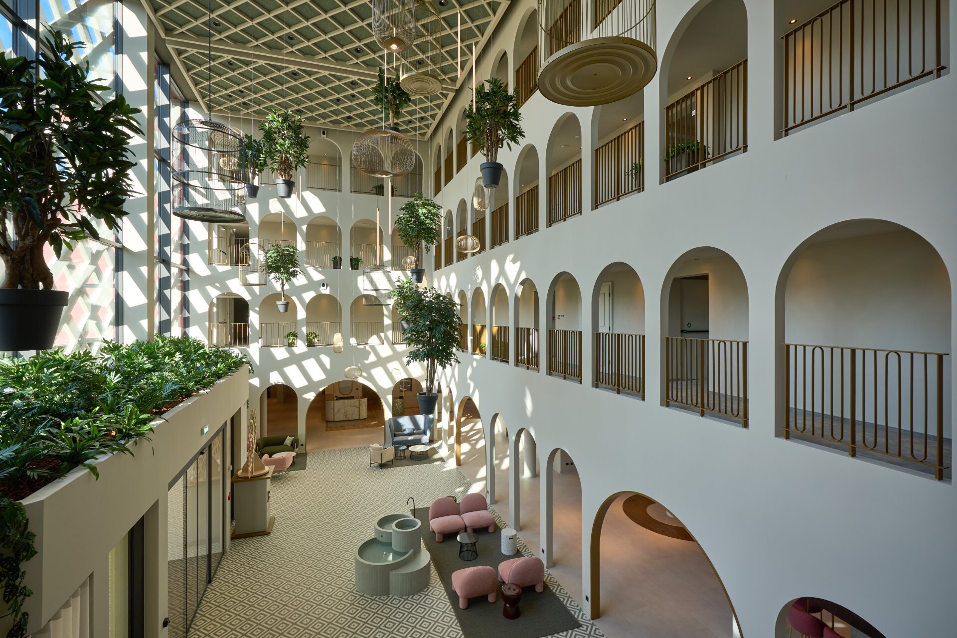 Spacious indoor hall in Venetian style with grand arches and plants at Cavallino Bianco Caorle.