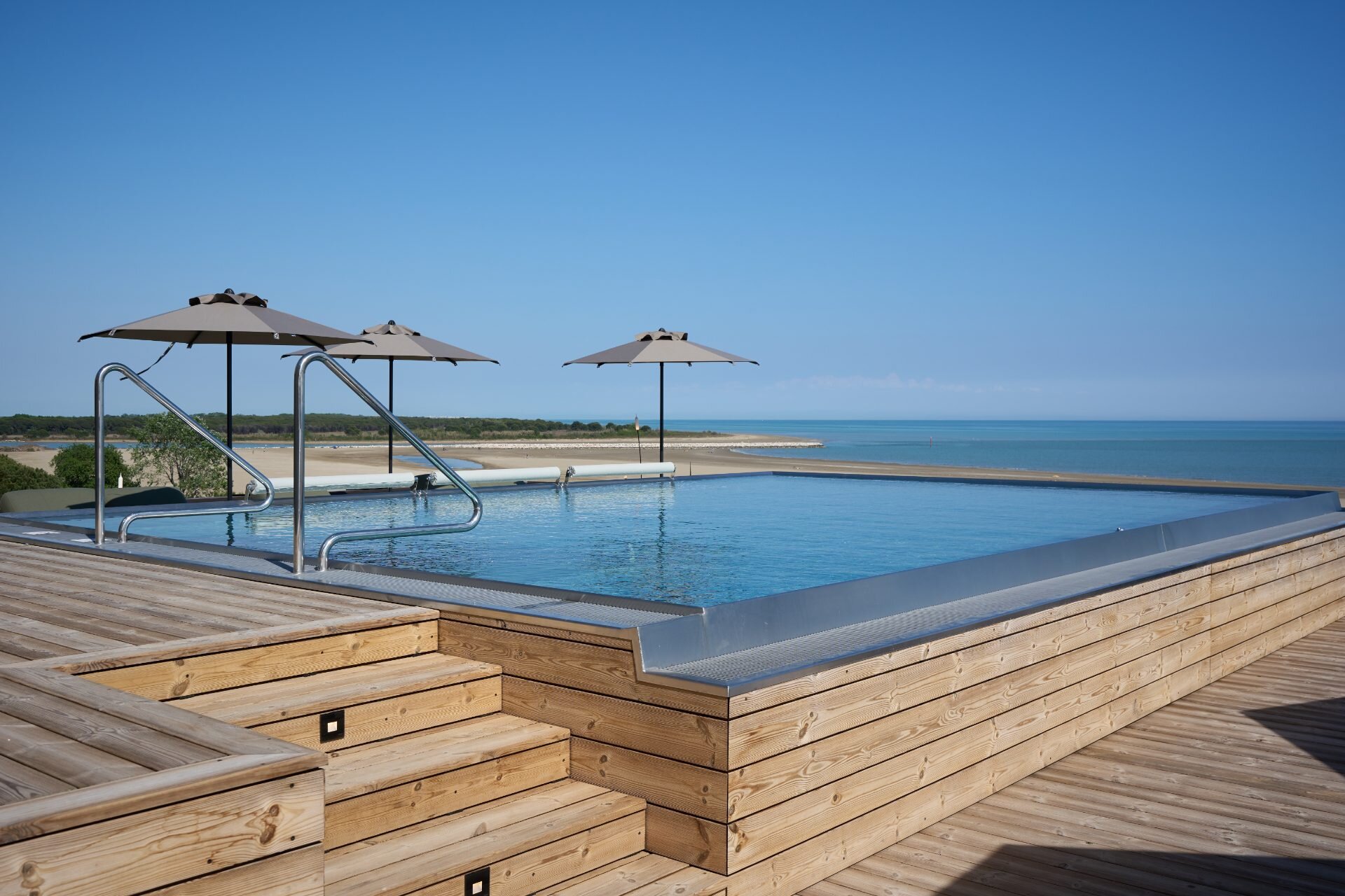 Piscina sul rooftop con vista panoramica sulla laguna e sul mare di Caorle al tramonto.