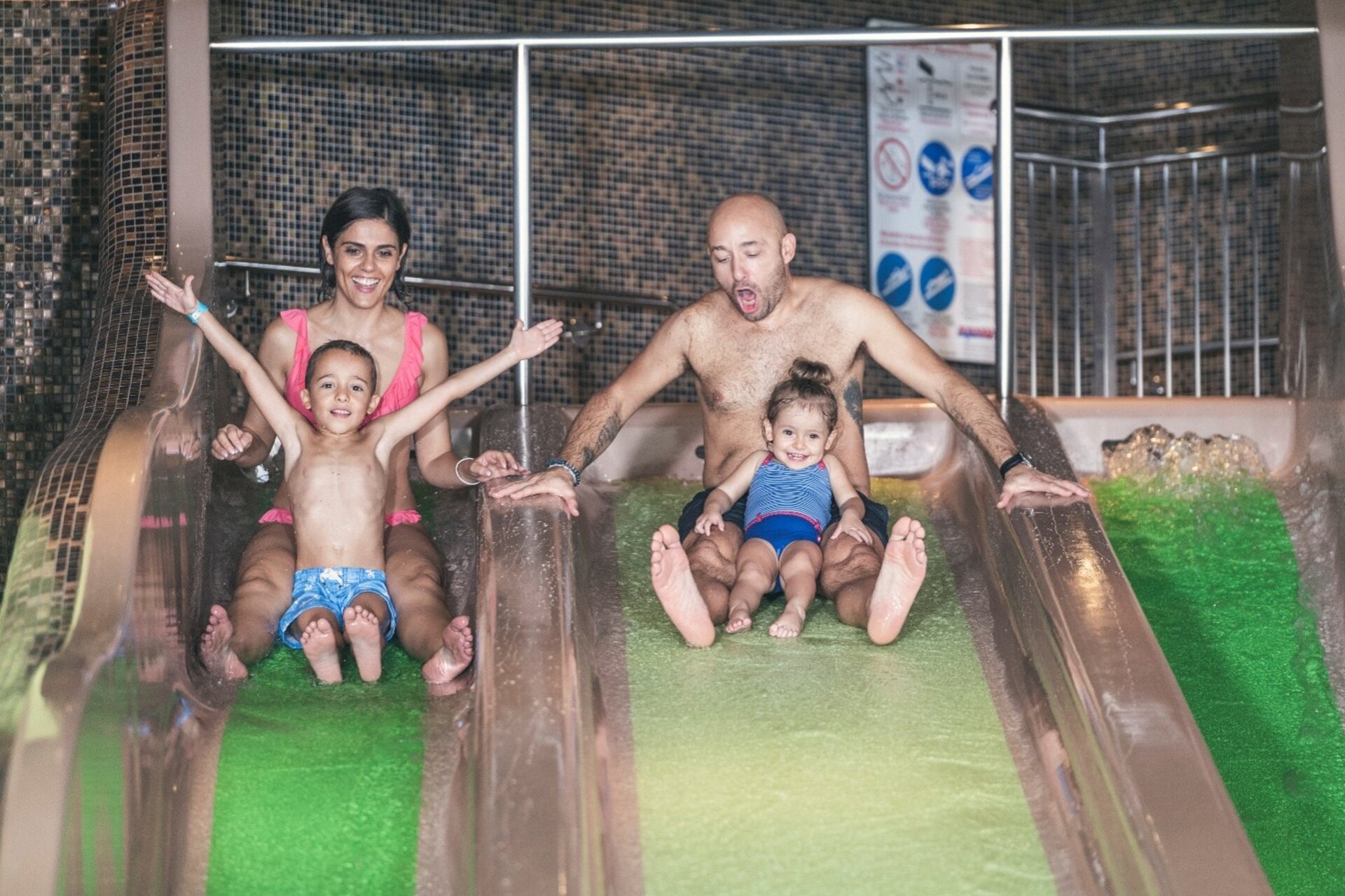 Famiglia con bambini sugli scivoli del miglior hotel per famiglie in montagna con piscine.