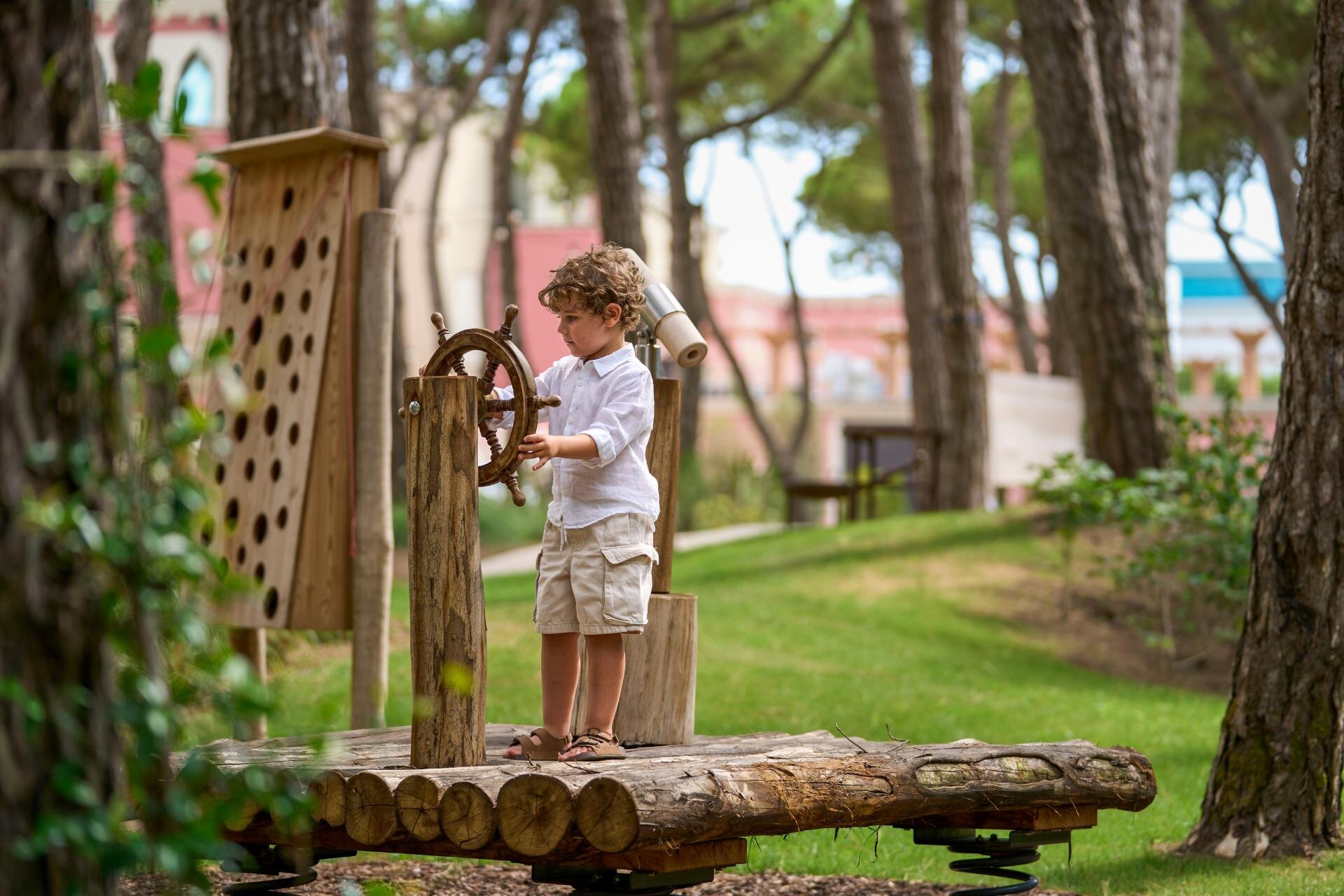 Bambino gioca con una struttura in legno nella pineta privata del Cavallino Bianco a Caorle
